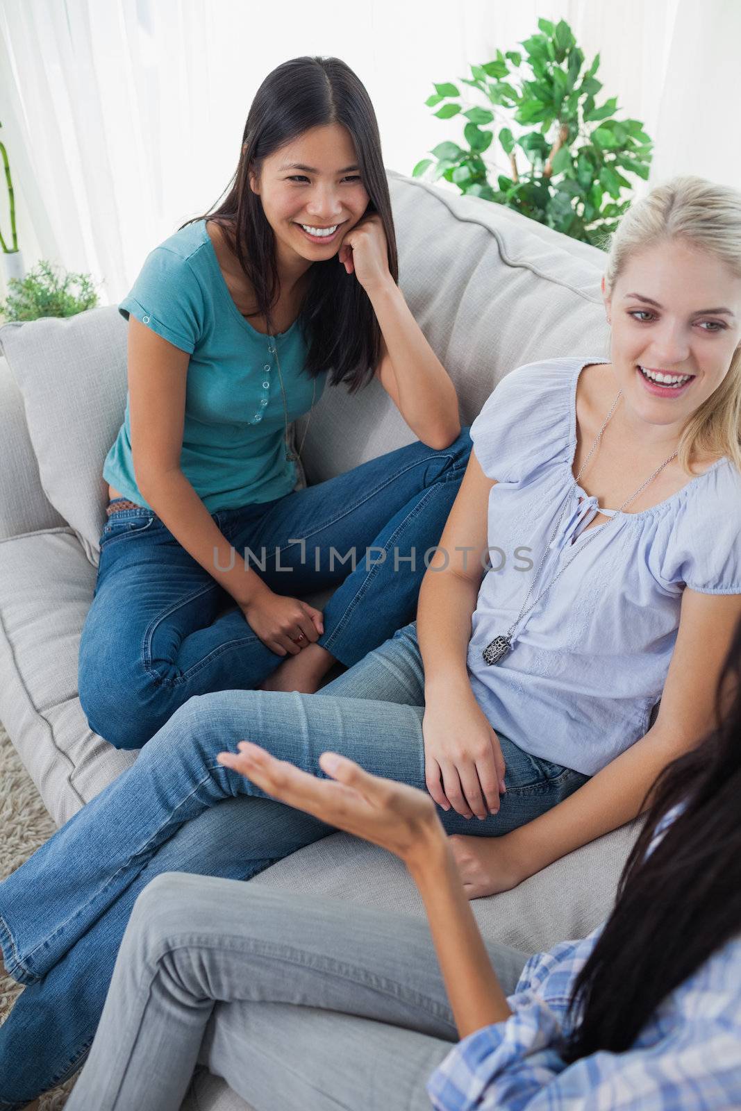 Friends having a chat and laughing at home on the couch
