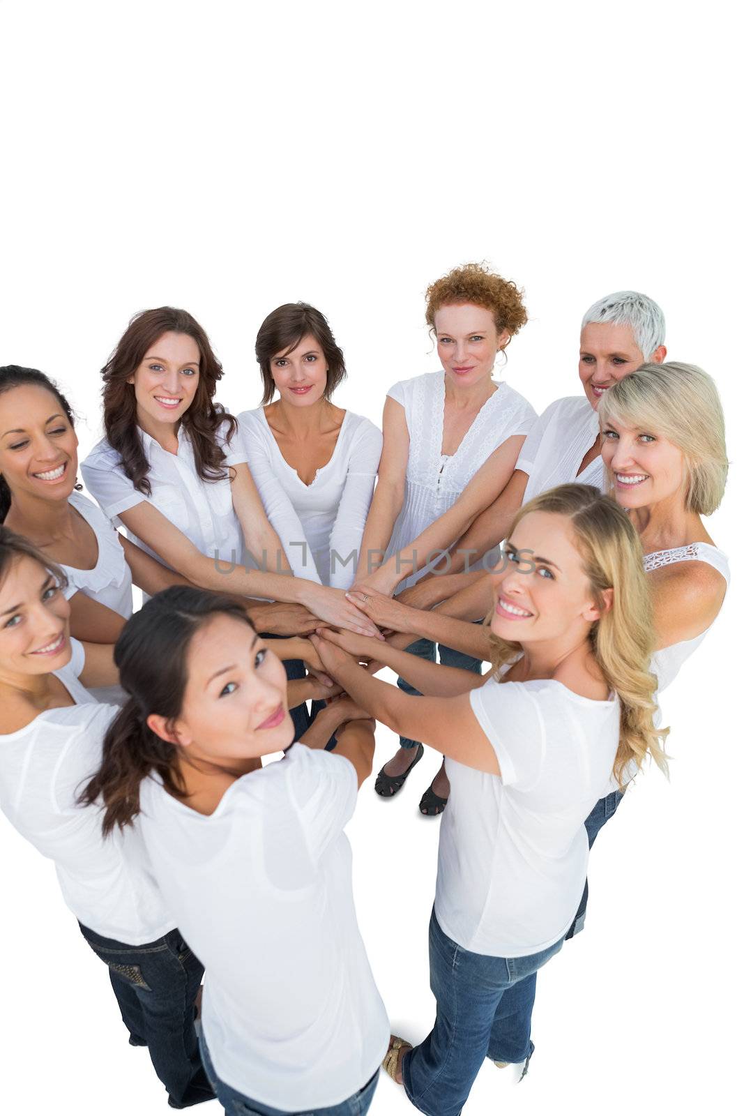Happy female models joining hands in a circle and looking at camera on white background