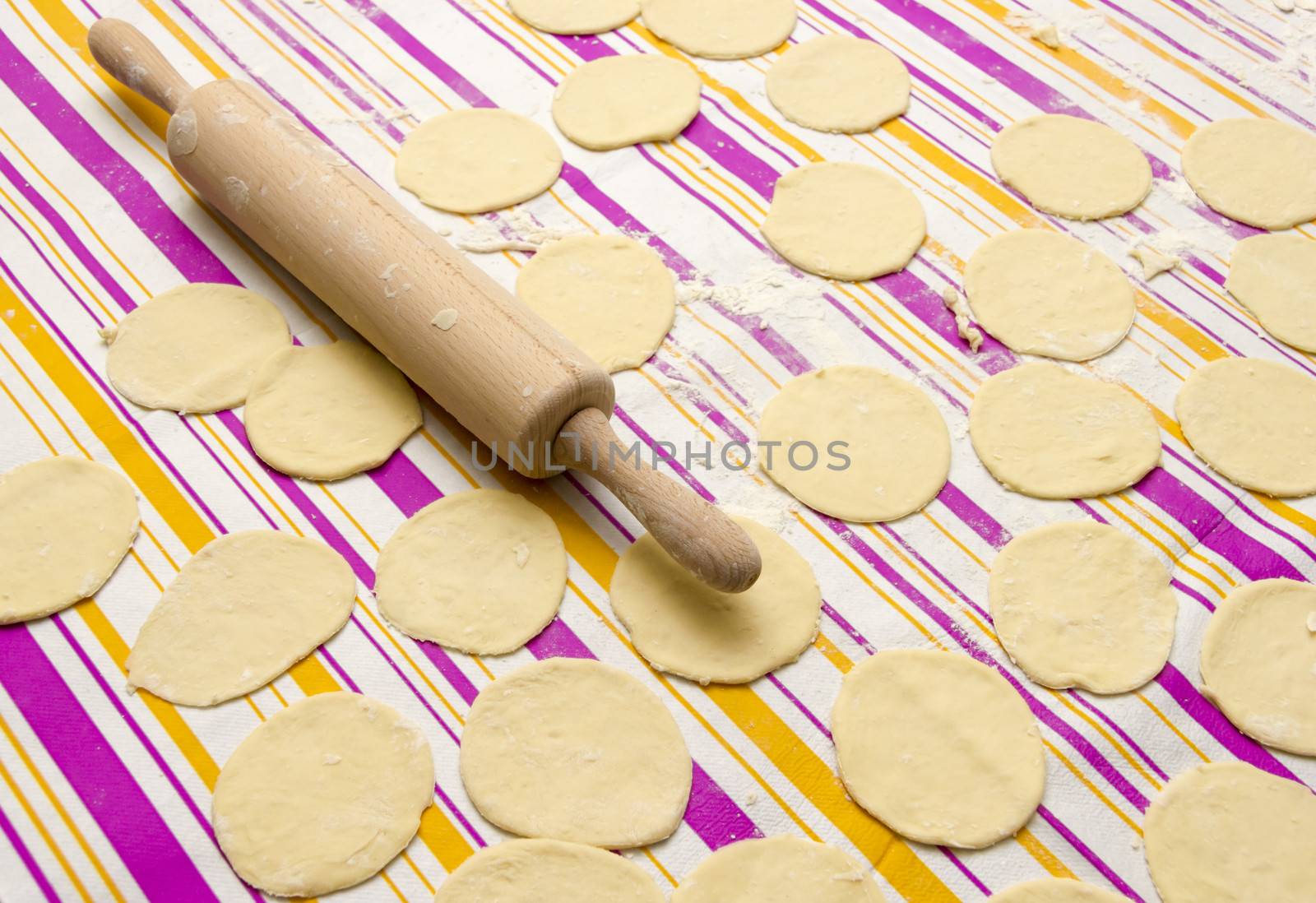round shape of the dough and rolling pin with flour on the table by Tetyana