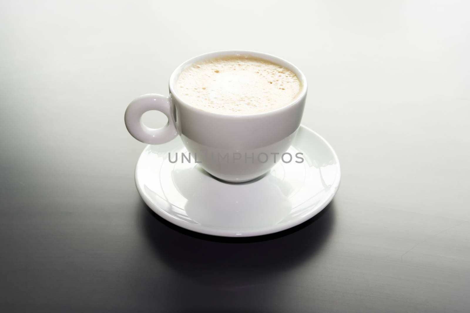white cup of cappuccino on a black matte surface by Tetyana