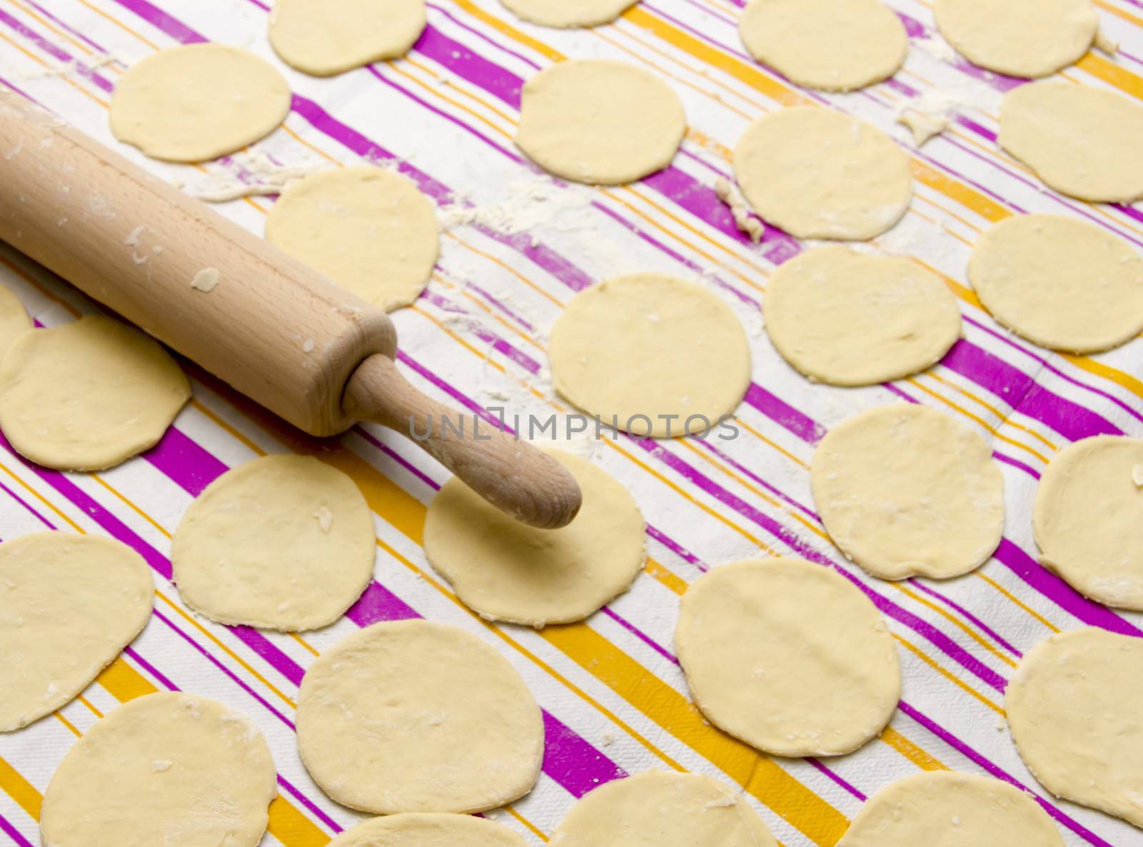 round shape of the dough and rolling pin with flour on the table by Tetyana