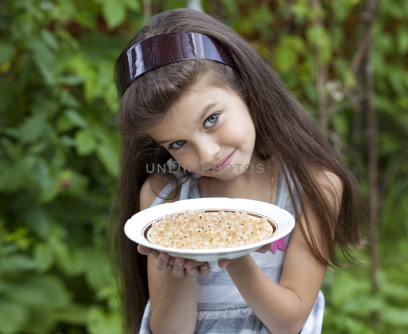 Little girl holding a plate with a white currants by andersonrise