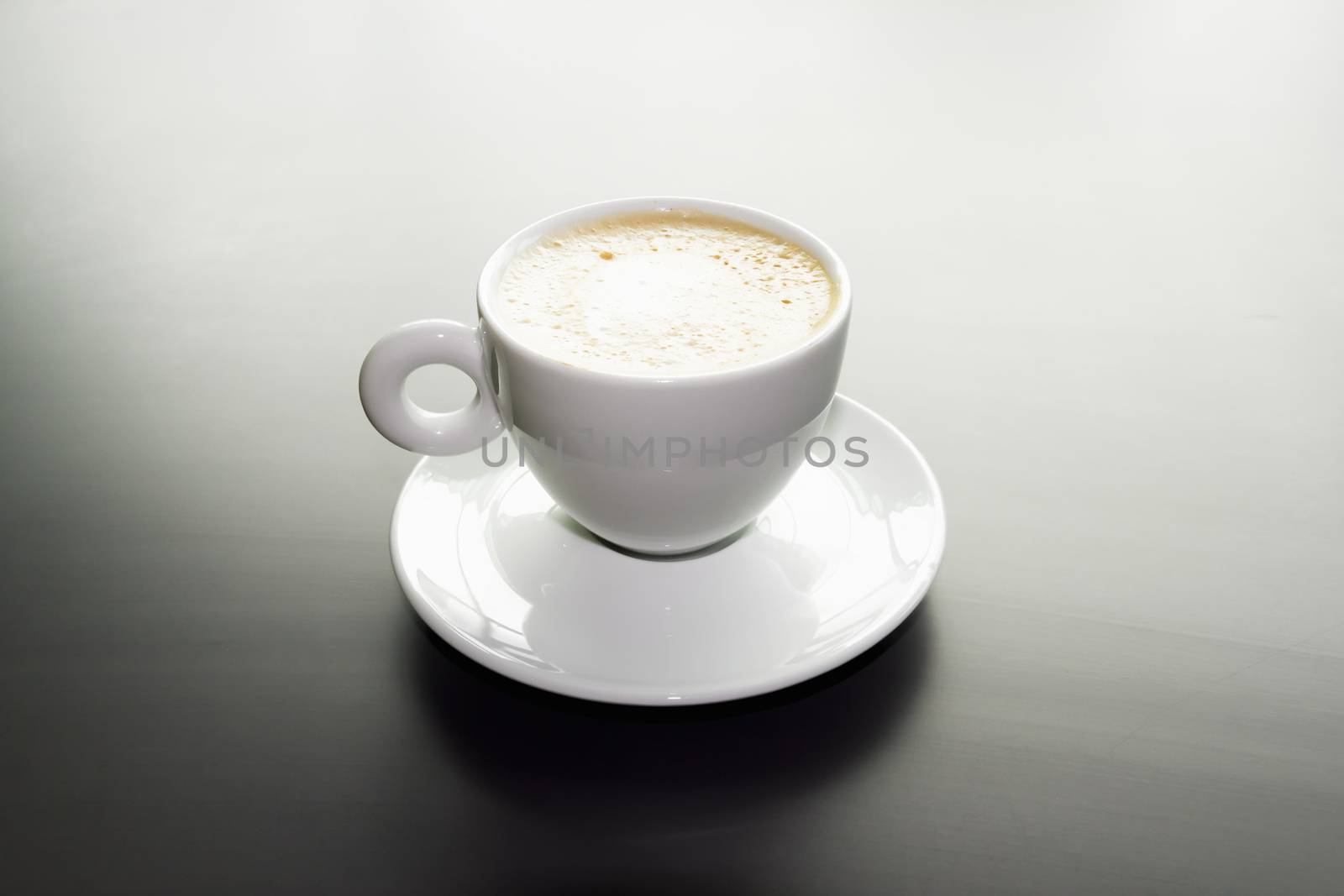 white cup of cappuccino on a black matte surface