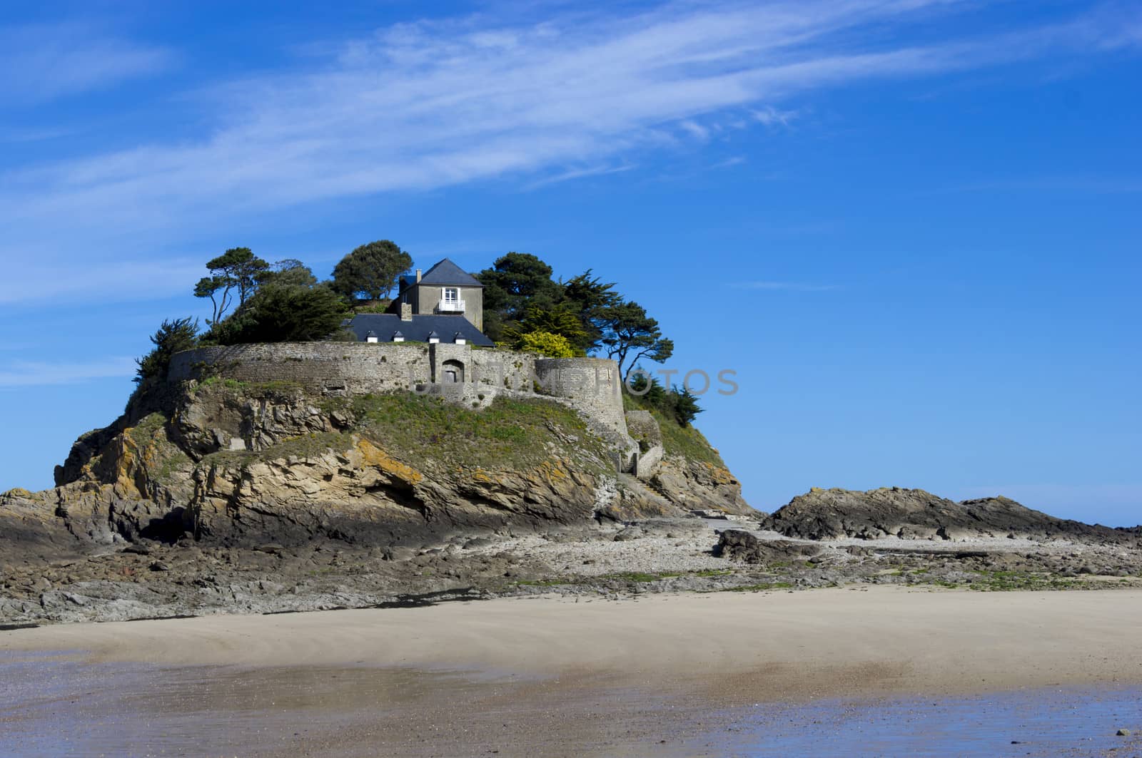 Landscape, seascape with beach and a house on top of a rock. 