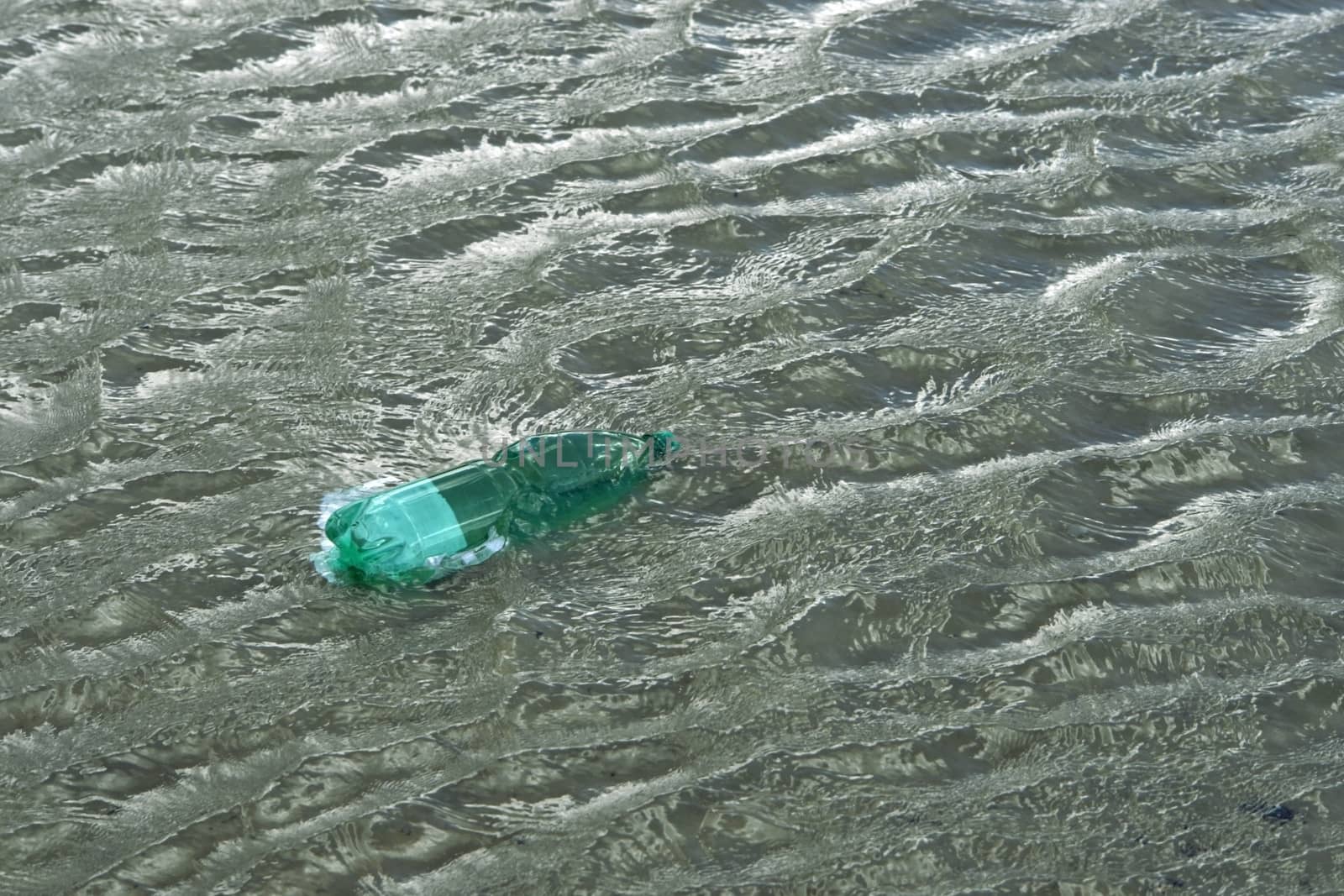 pollution theme with a green plastic bottle floating on water surface