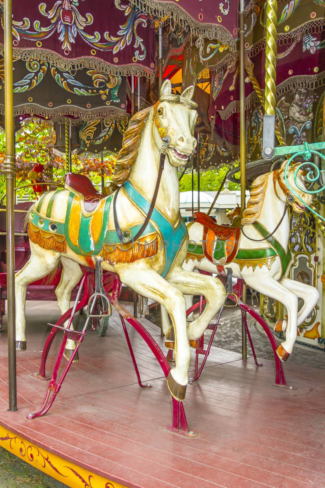 Two colourful horses in a vintage (old fashioned) carousel by Tetyana