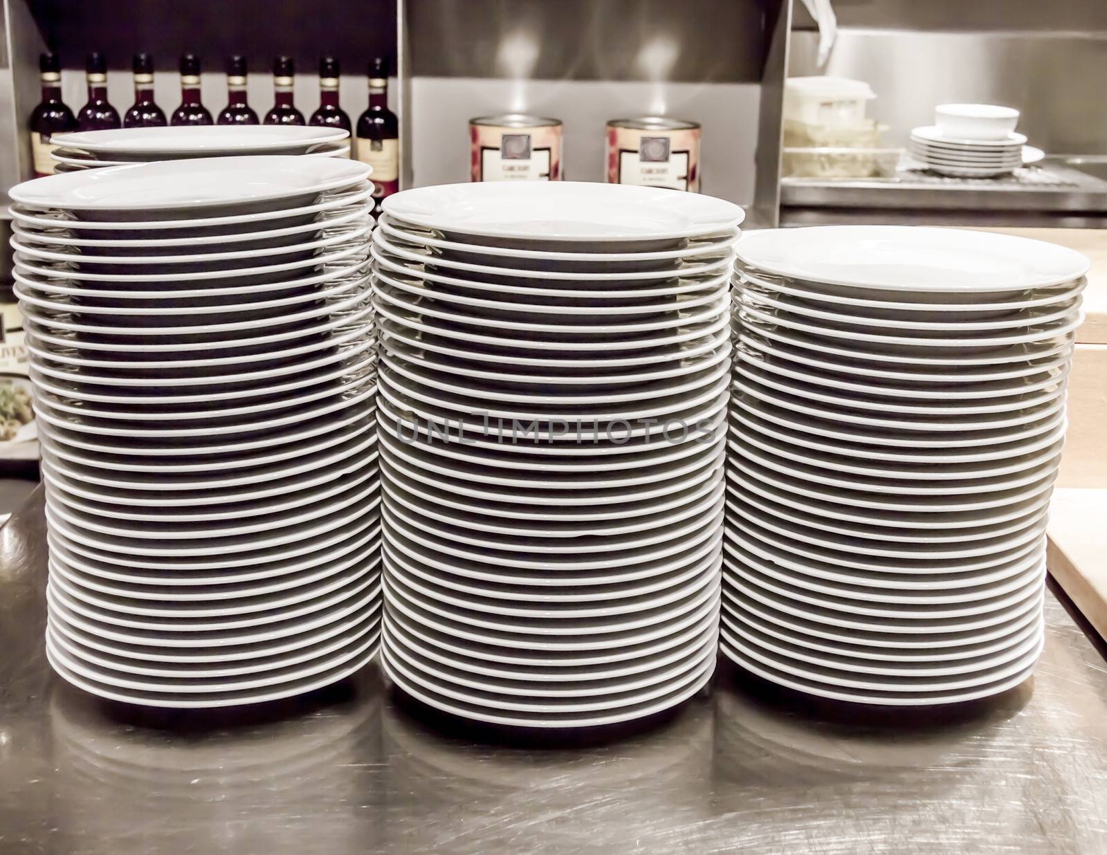 Stacks of white plates against a restaurant background by Tetyana