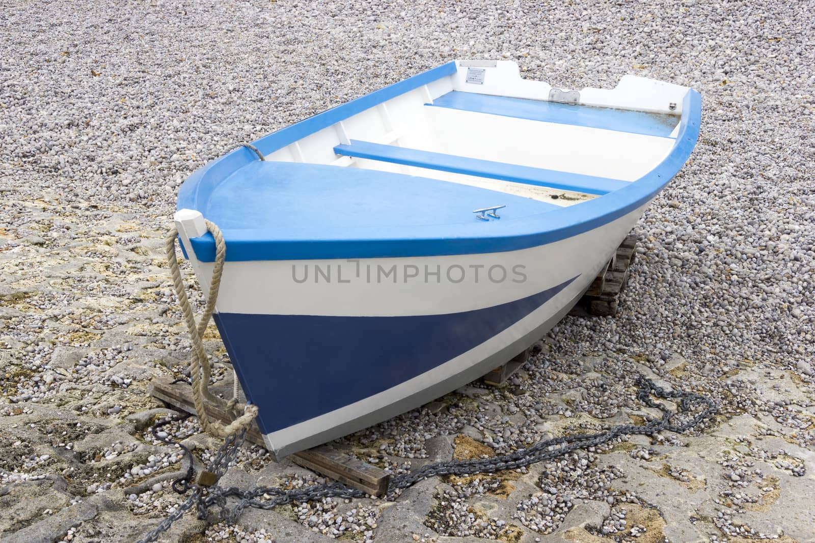 Blue and white boat on the shingle beach by Tetyana