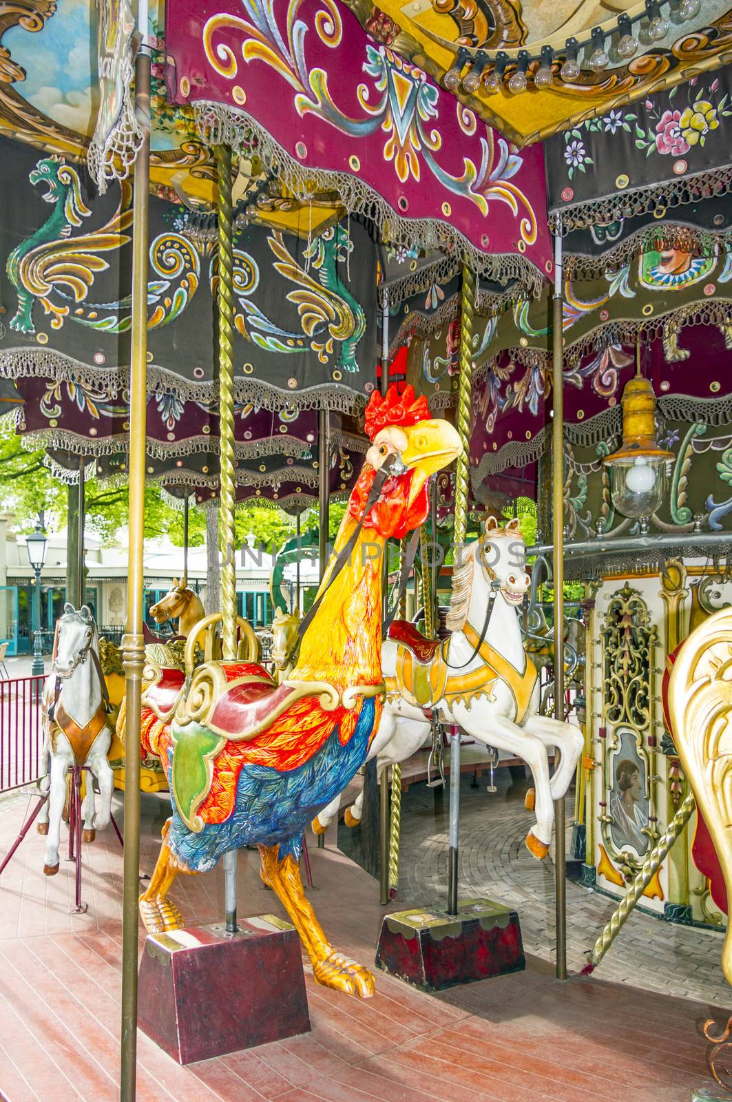 Colorful horses and cock in vintage carousel by Tetyana