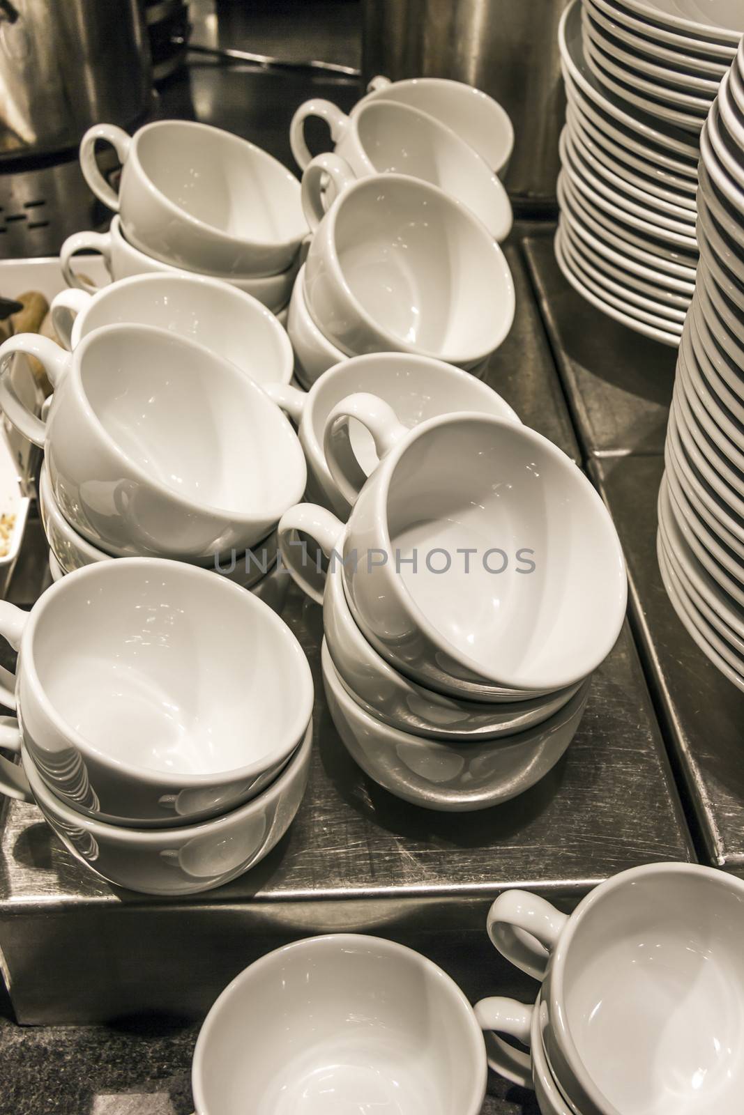 Stacks of white bowls against a restaurant background by Tetyana