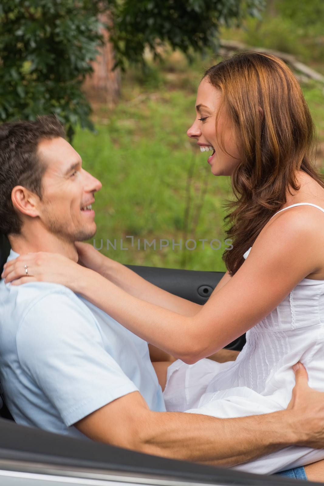 Happy couple feeling romantic in back seat and laughing by Wavebreakmedia