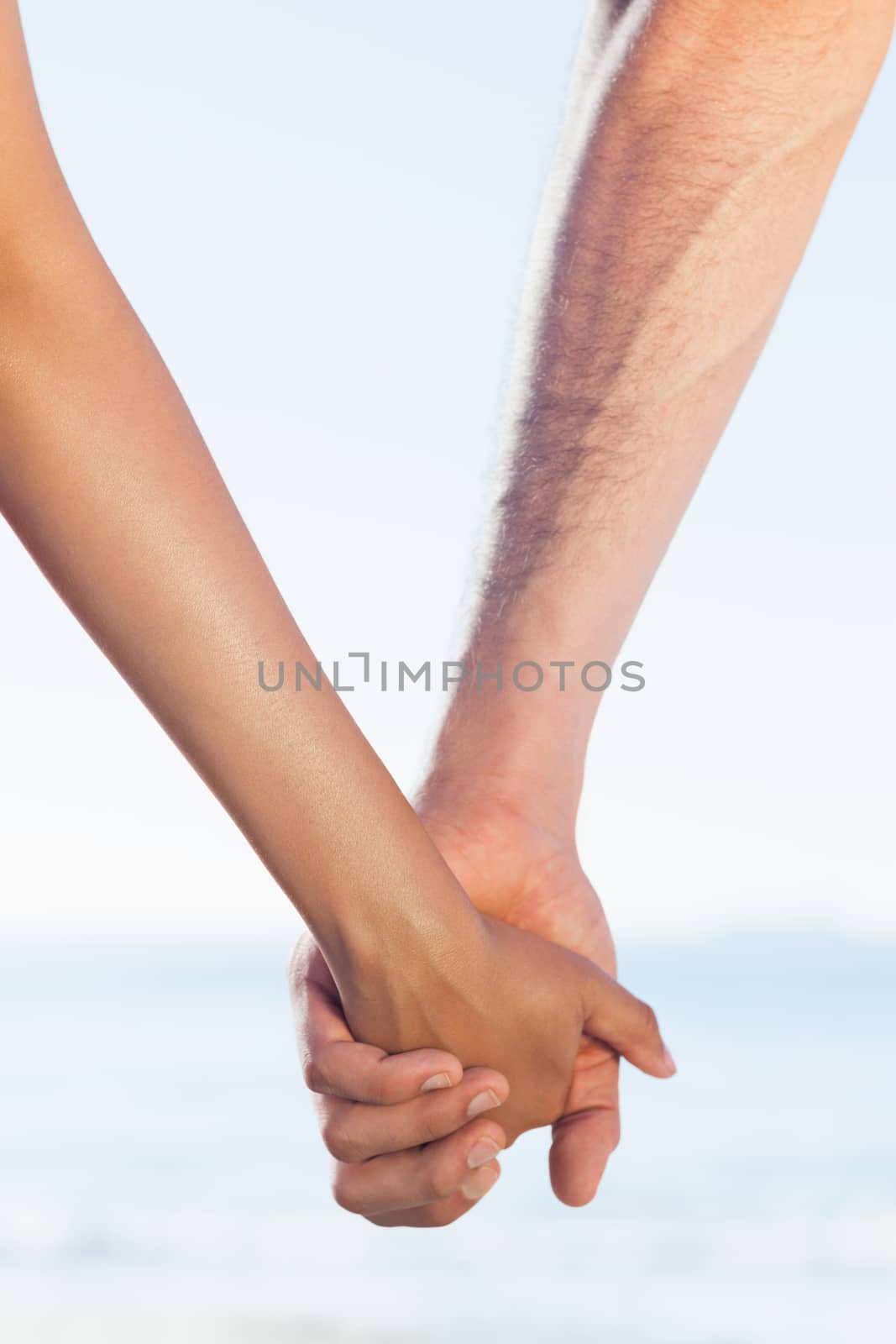 Loving young couple grasping hands on the beach
