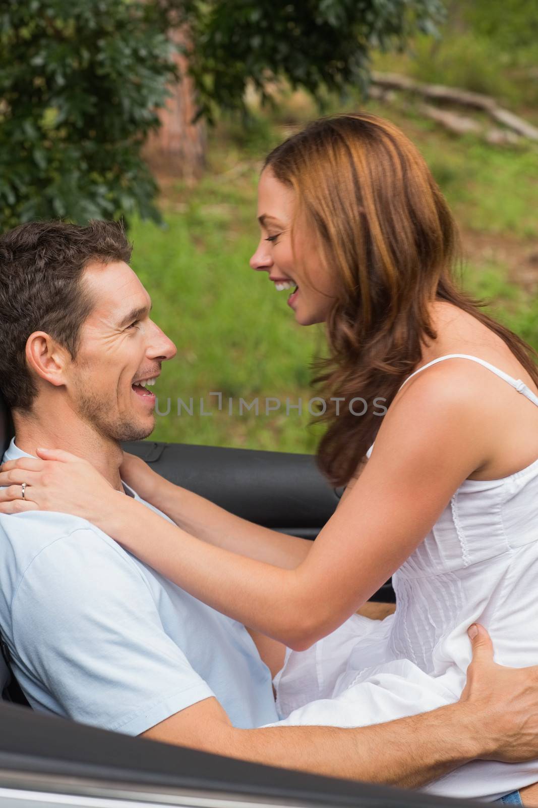 Young couple feeling romantic in back seat and laughing in a convertible in countryside