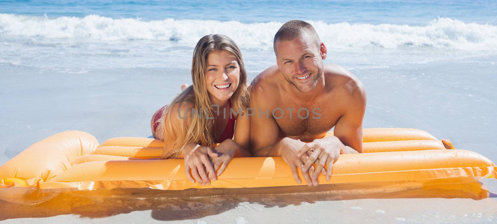 Happy cute couple in swimsuit lying on the beach together