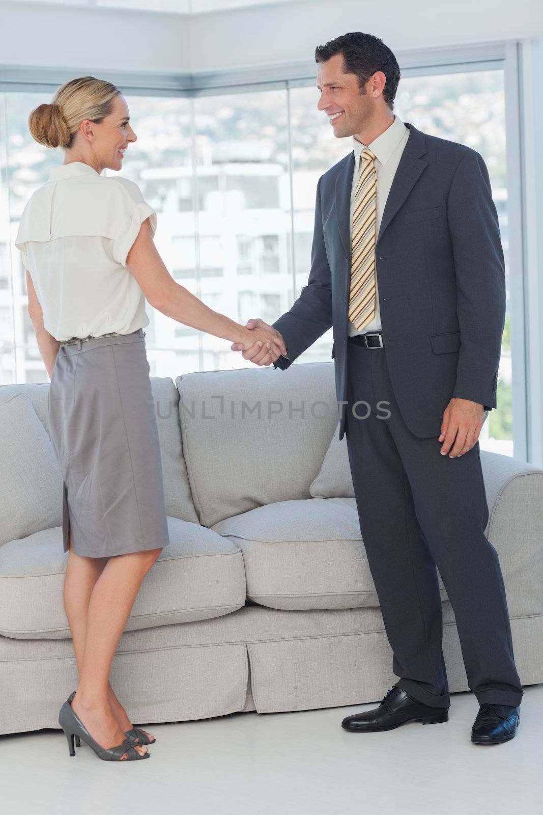 Cheerful business people shaking hands in bright office