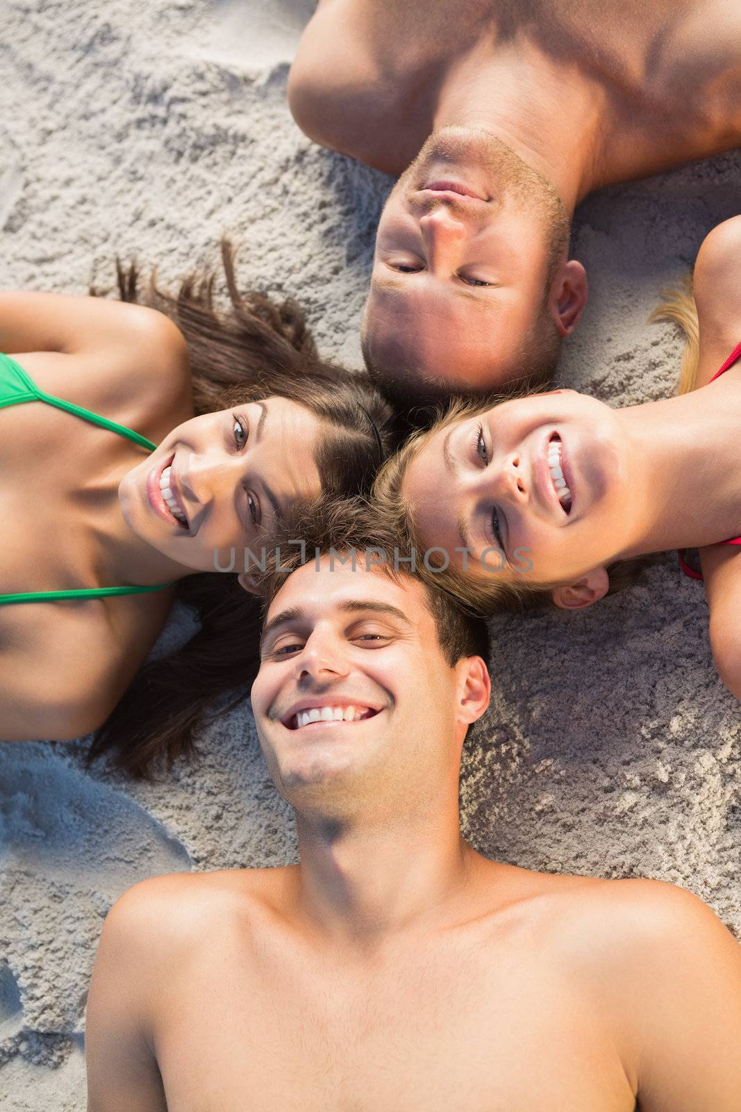Overhead of cheerful friends lying together in a circle by Wavebreakmedia