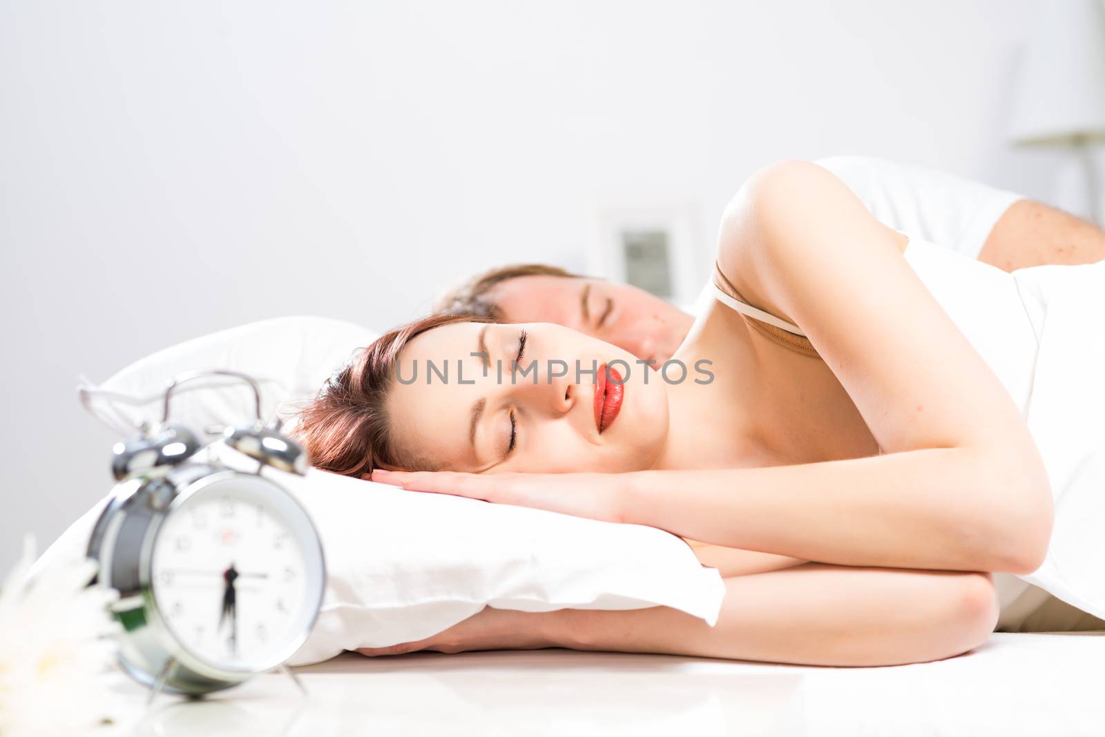 young beautiful woman sleeping on the bed with her husband
