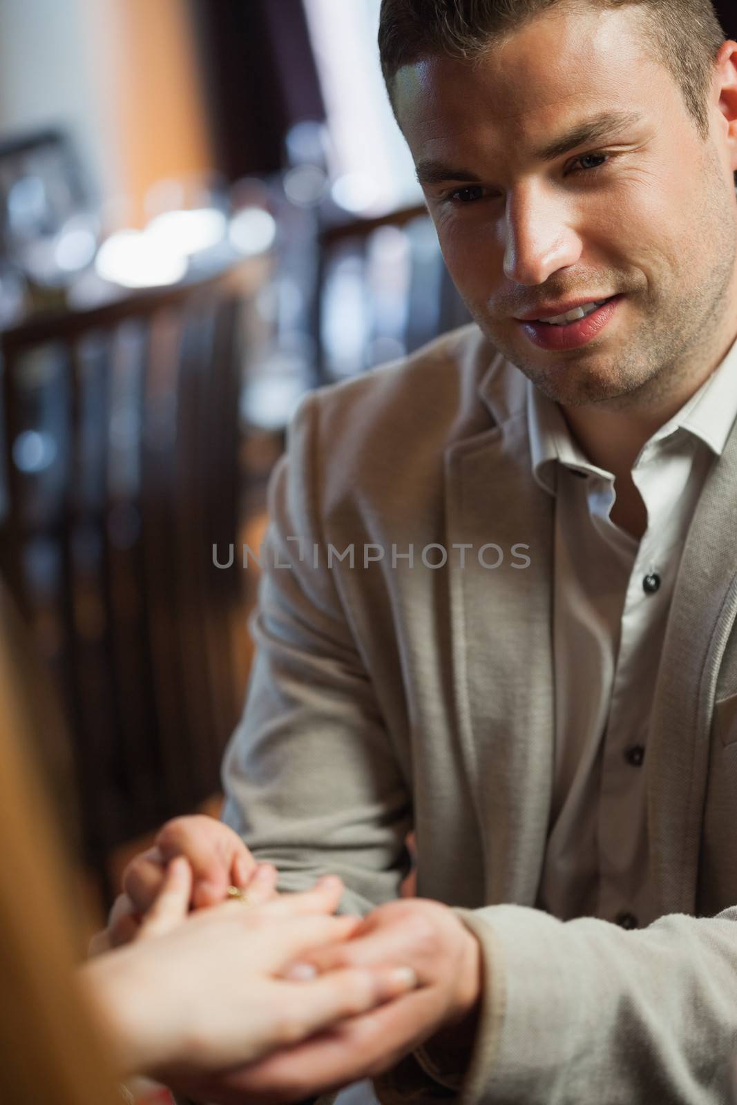 Handsome man putting on ring on his fiances finger by Wavebreakmedia