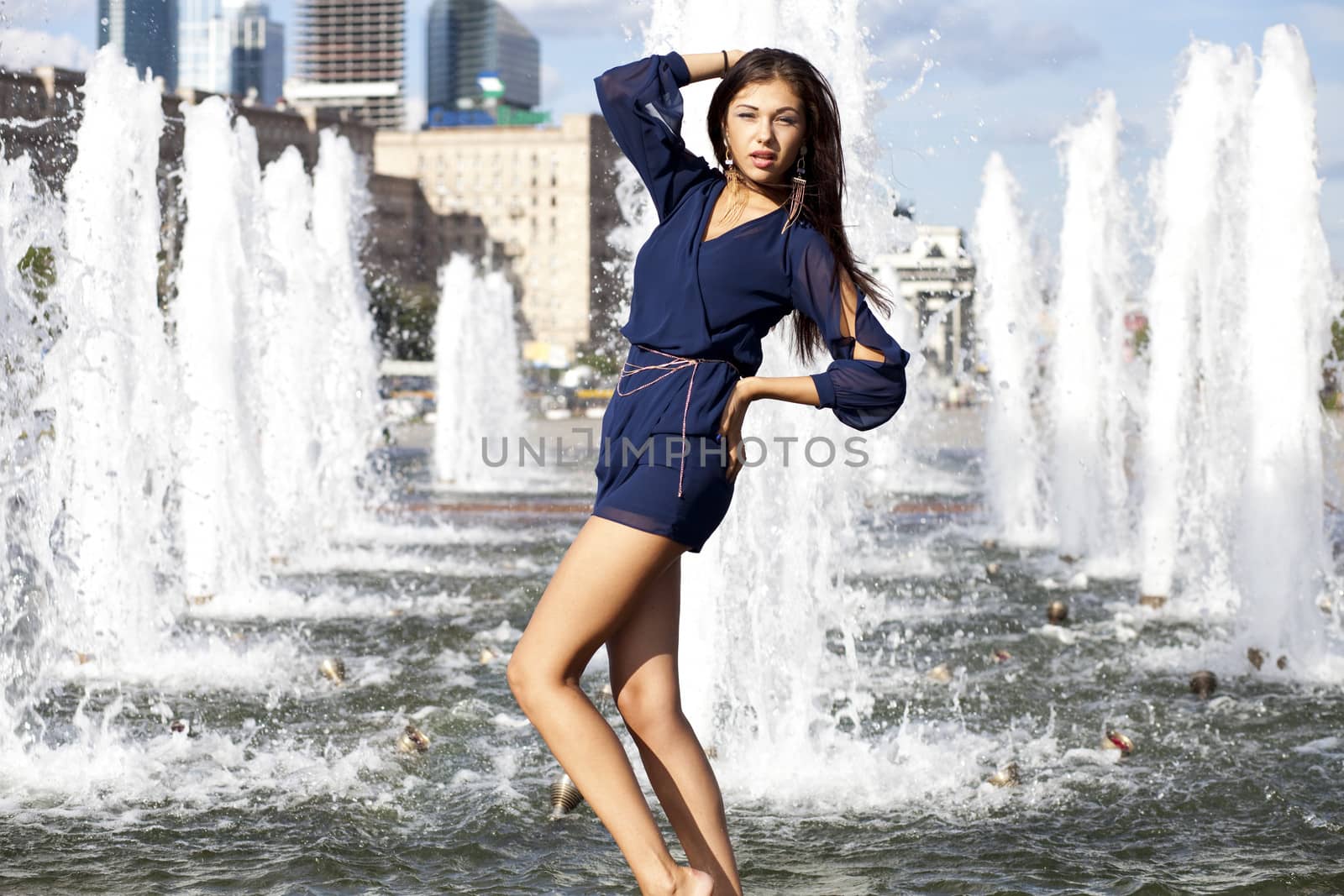 Young sexy woman in a city fountain