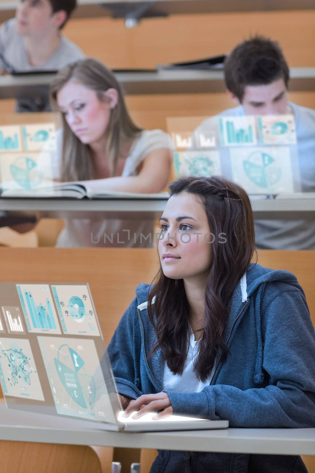 Serious pretty student working on her futuristic laptop in lecture hall