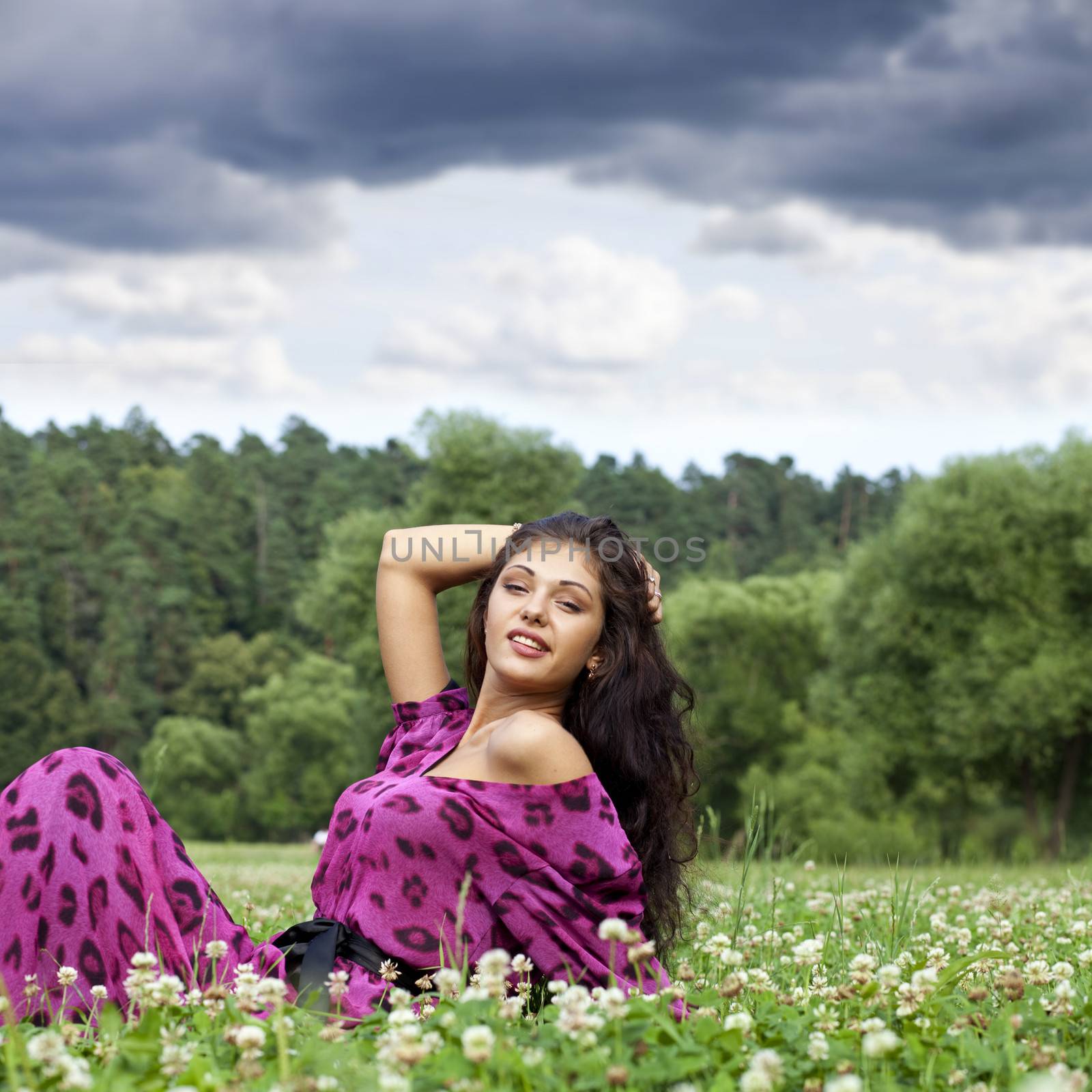 Portrait of young woman sitting on a green lawn