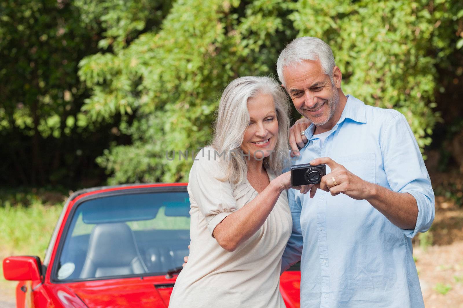 Cheerful mature couple looking at pictures on their camera by Wavebreakmedia