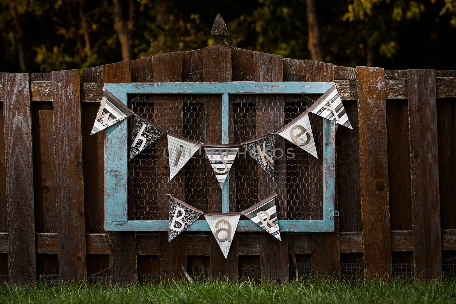Blue vintage whiskey bar sign hanging on a fence outside for a wedding.