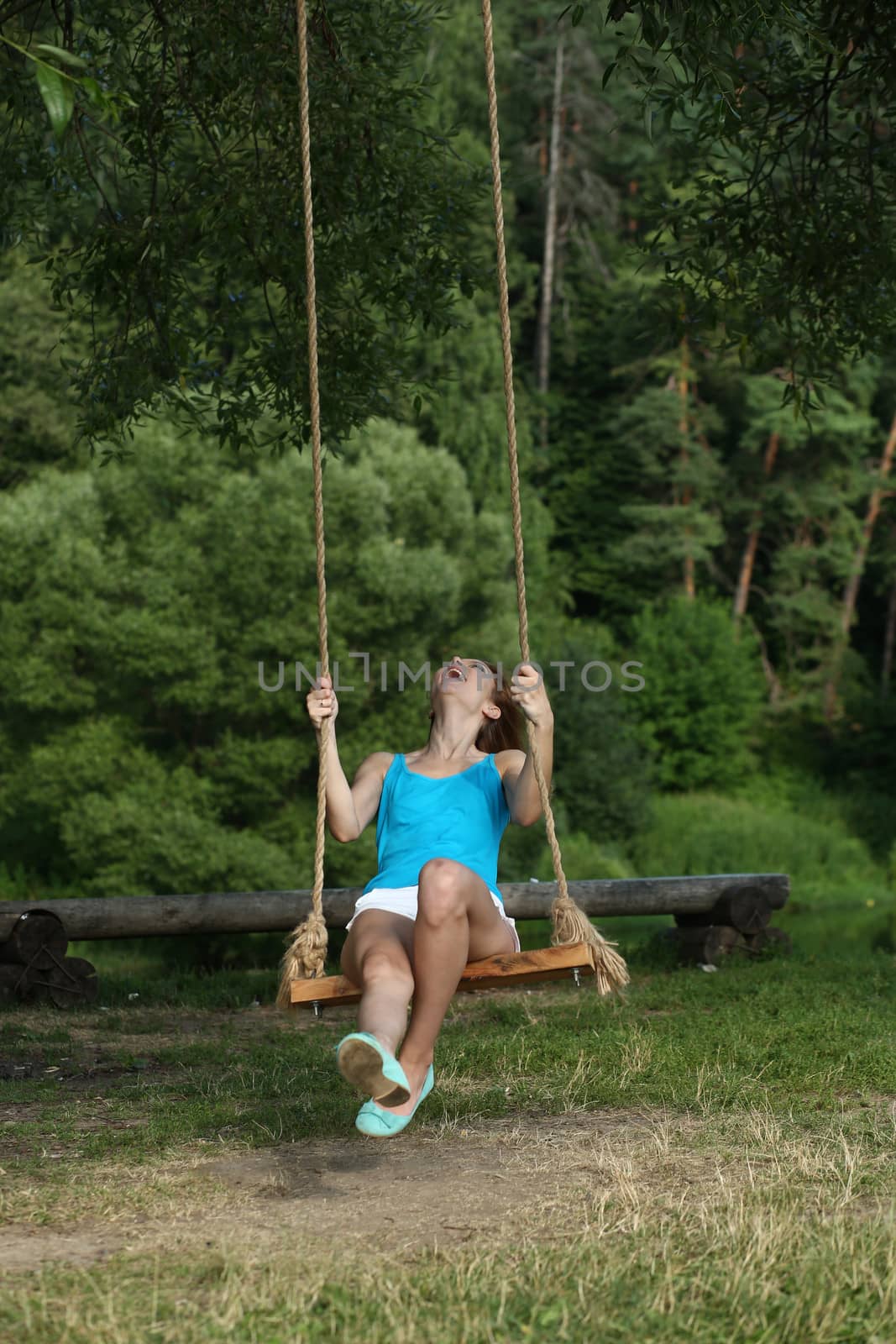 Young happy woman riding on a swing in the park