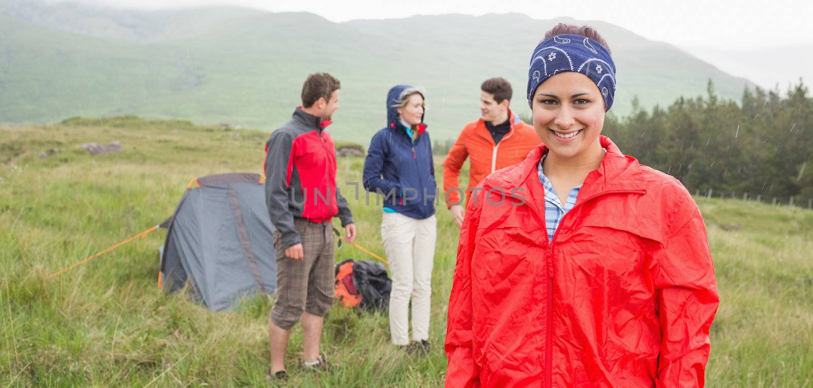 Brunette smiling at camera with friends behind her on camping trip by Wavebreakmedia