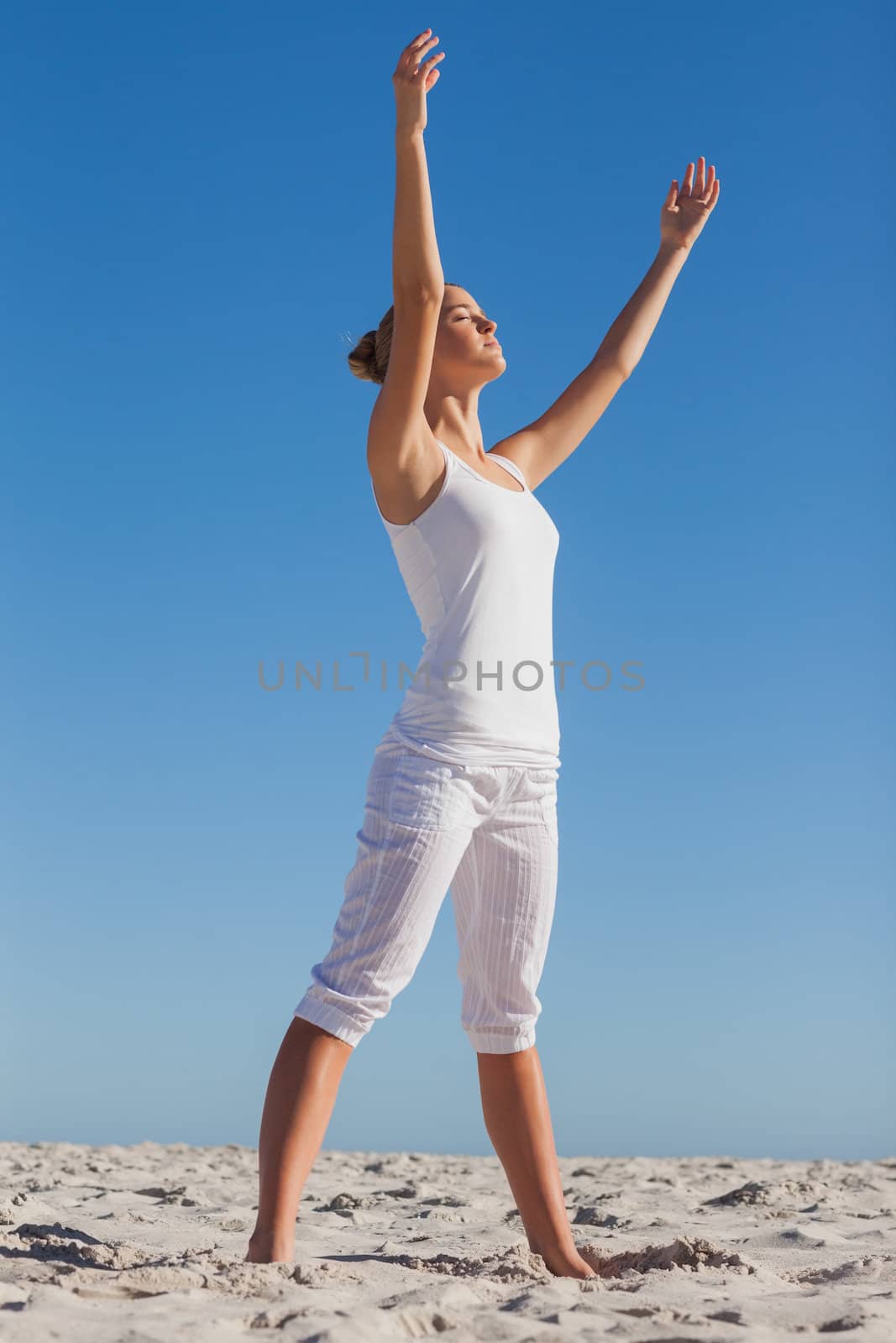 Woman practicing yoga at beach on a sunny day