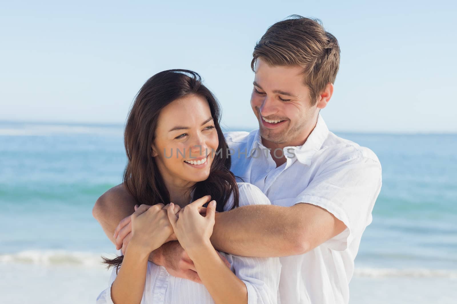 Cheerful couple relaxing and embracing on the beach during summer