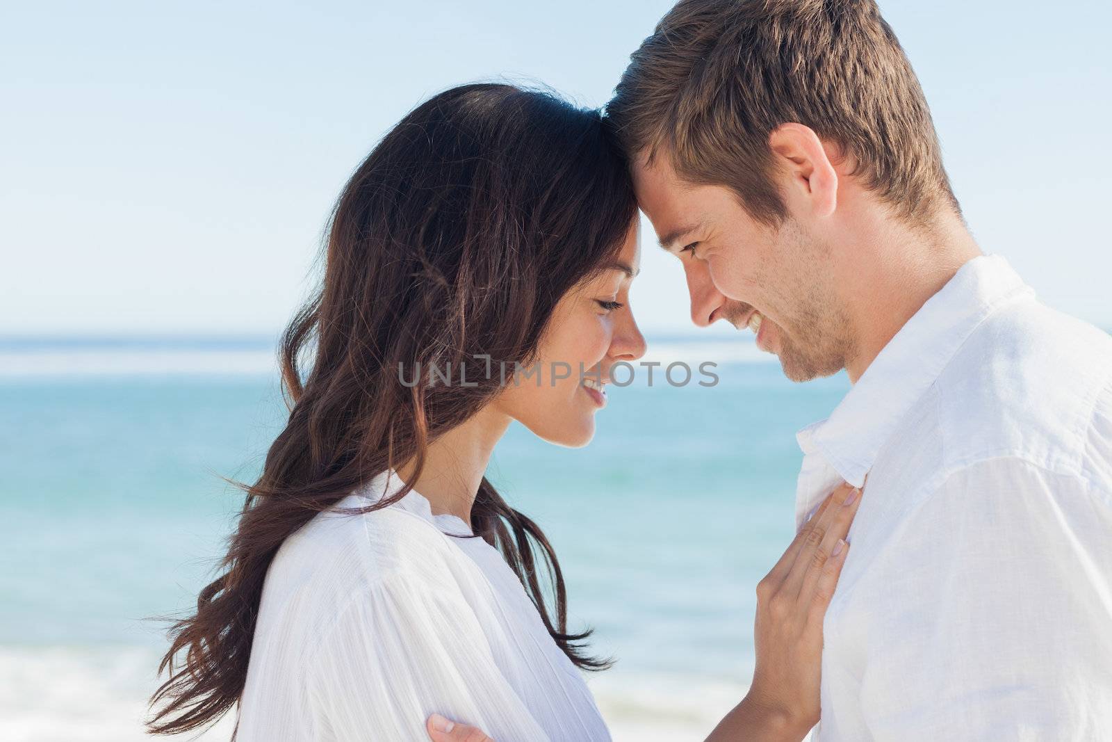 Romantic couple relaxing and embracing on the beach during the summer