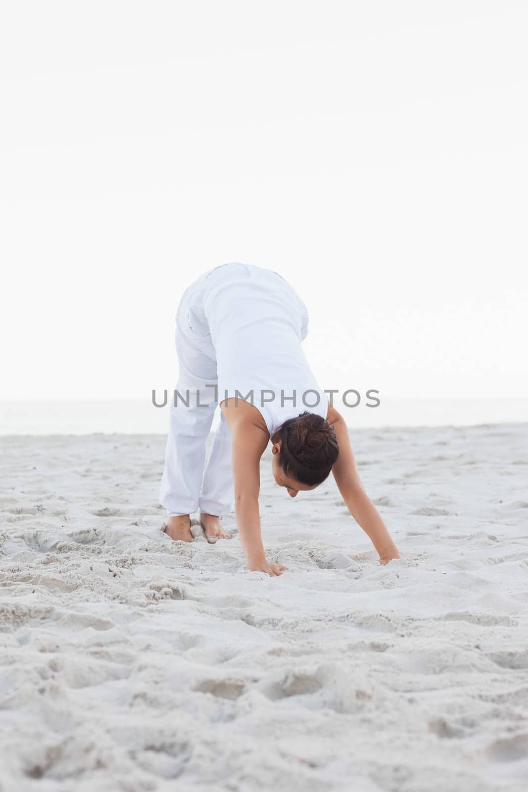 Woman doing extended triangle yoga pose at the beach