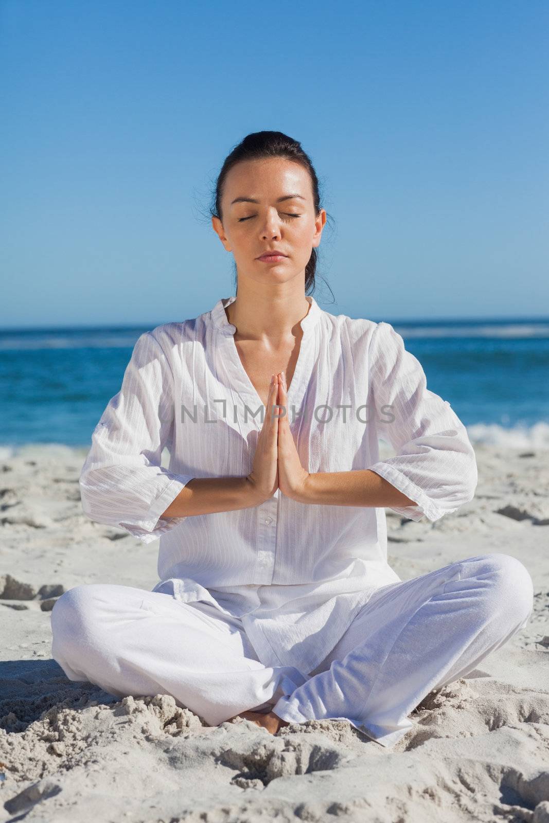 Woman practicing yoga at the beach on a summers day