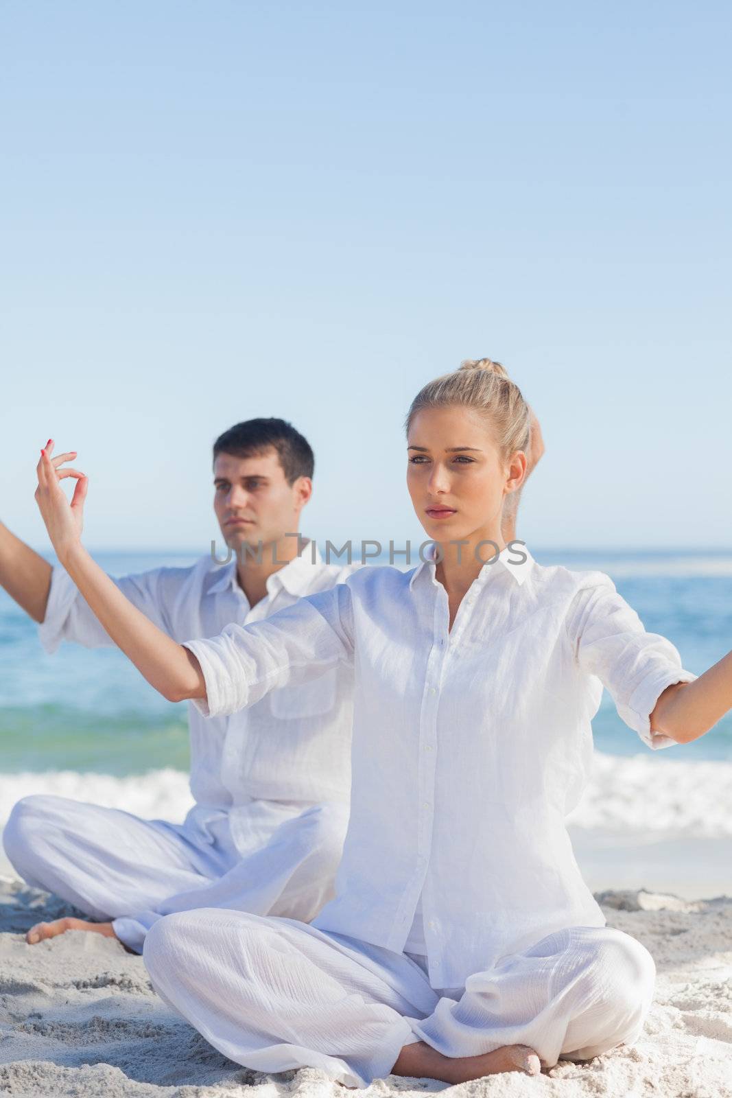 Attractive people doing yoga exercises at beach on a sunny day