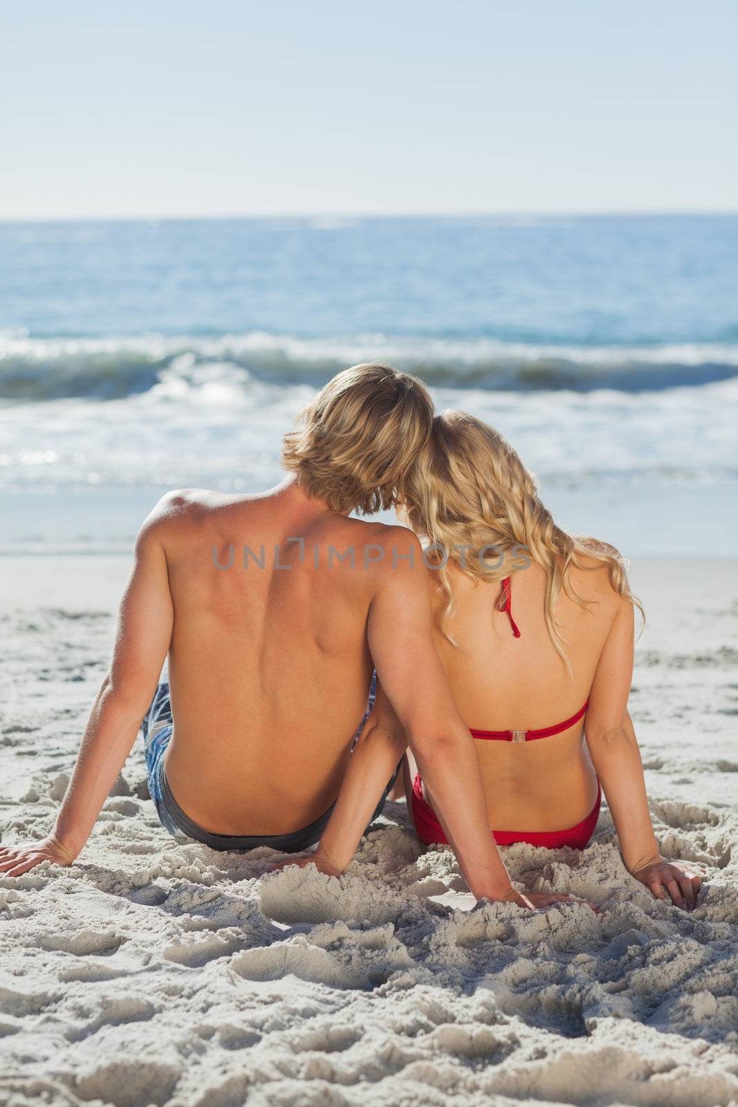 Rear view of a happy tanned couple sitting by Wavebreakmedia