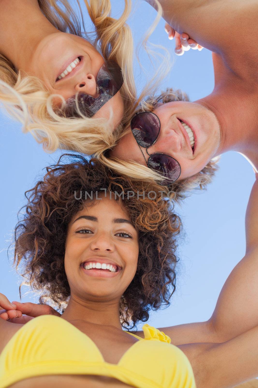 Low angle view of friends on beach smiling at camera