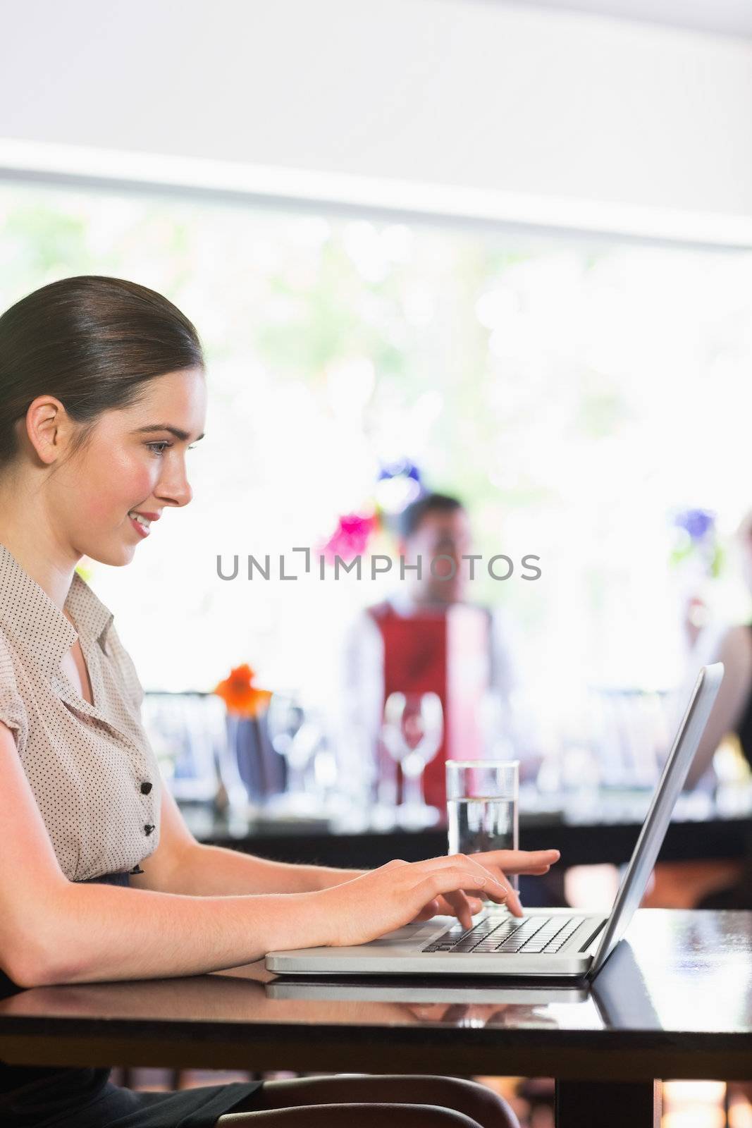 Smiling businesswoman working and laptop and looking on screen in a restaurant