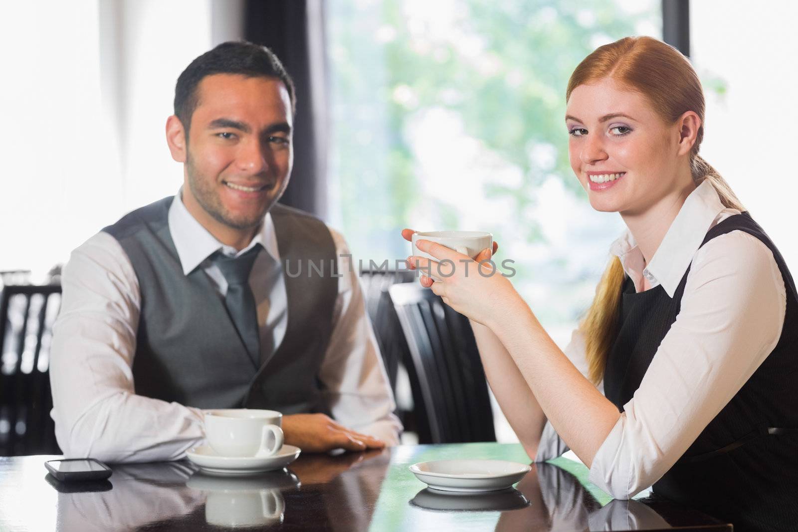 Business people having coffee and looking at camera in a cafe