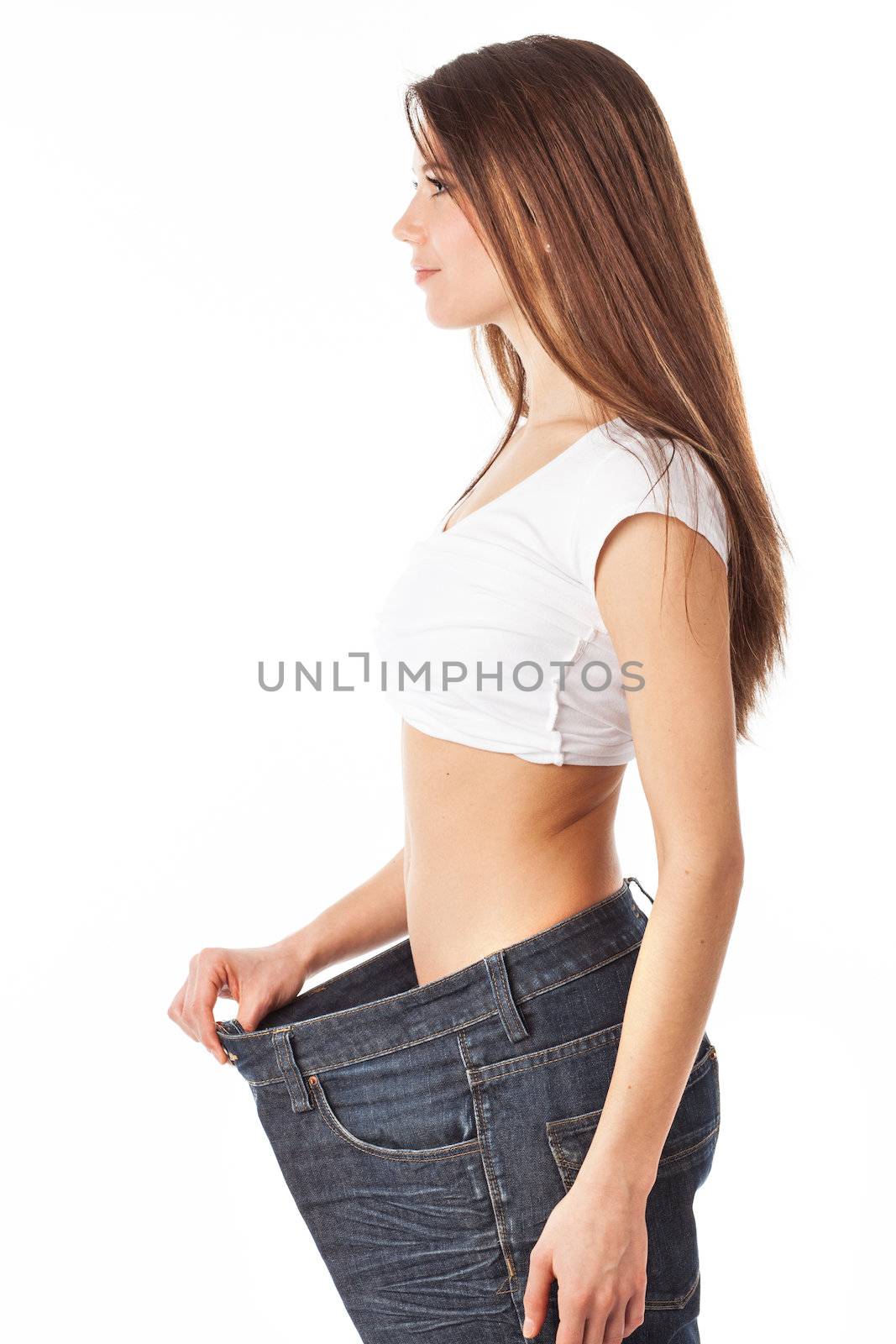 Young pretty woman showing how much weight she lost, isolated on white
