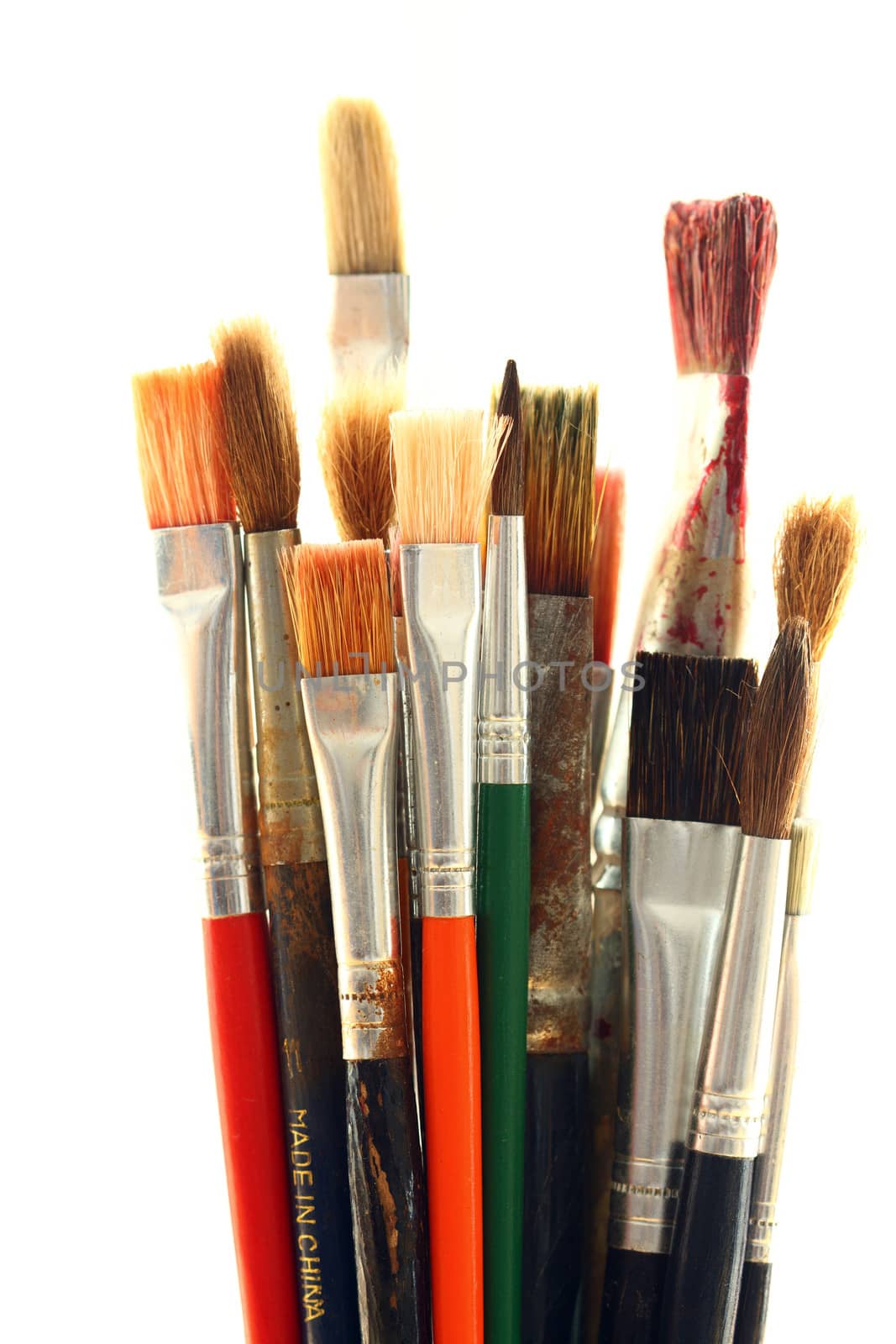 Old and used colorful paintbrushes over white