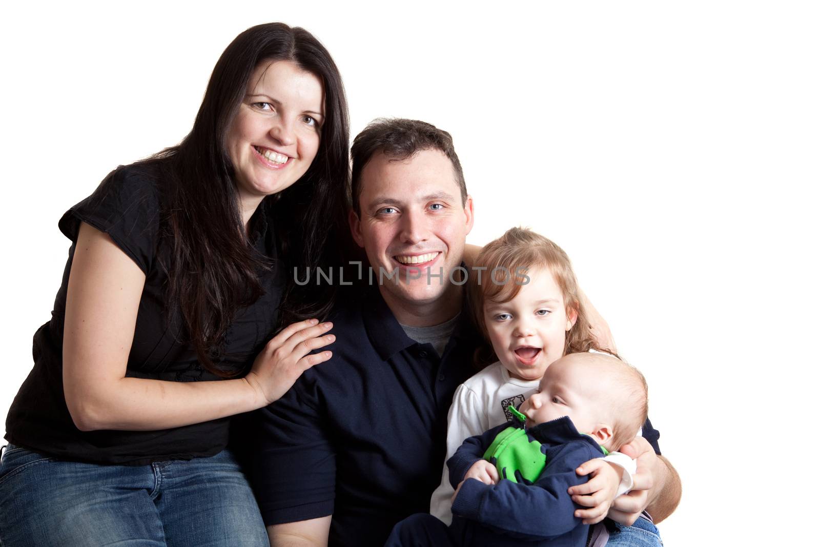 A young happy and healthy family isolated over white holding their newborn baby boy and toddler age daughter.