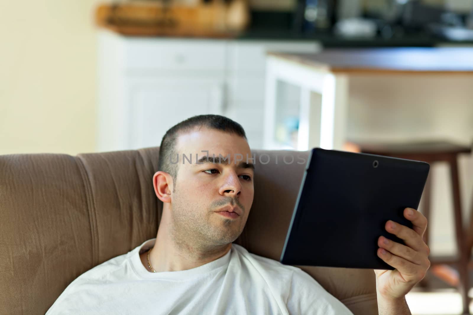 Guy holding and reading something on his portable tablet computer.