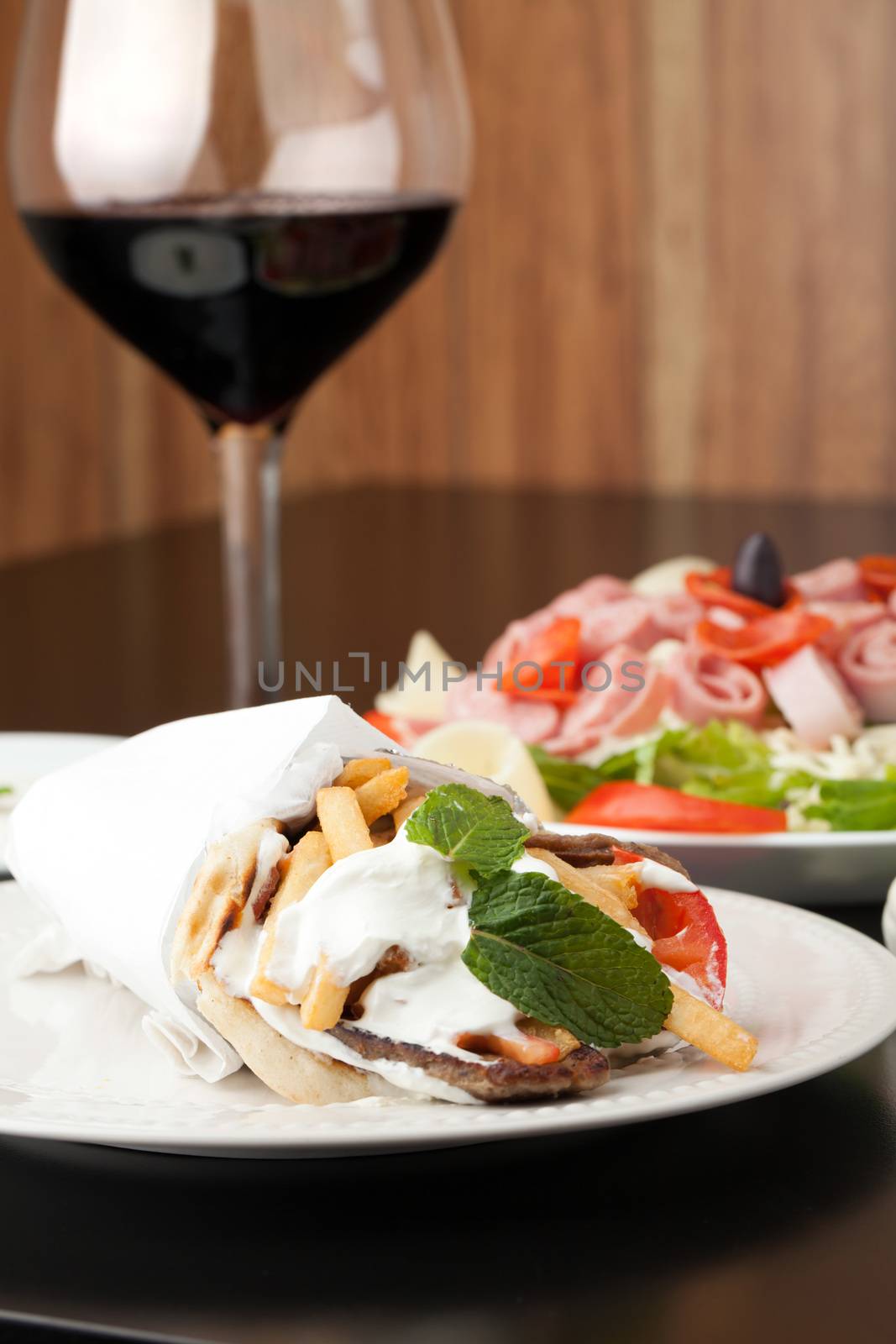Traditional Gyro sandwich with meat  tzatziki sauce tomato onions and fried potato garnished with mint. Shallow depth of field.