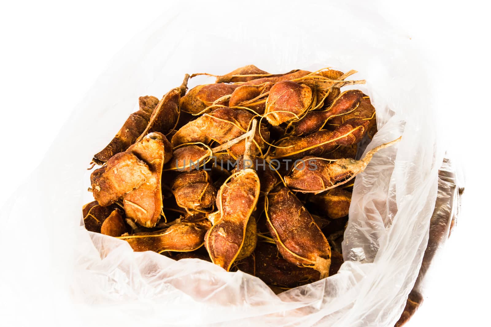 Chunk of fresh Tamarind, Thai tamarind can make sour soup's ingredient in plastic bag on a white background.