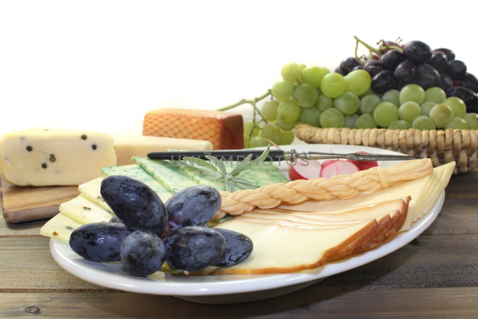 a white plate with various cheeses and radishes