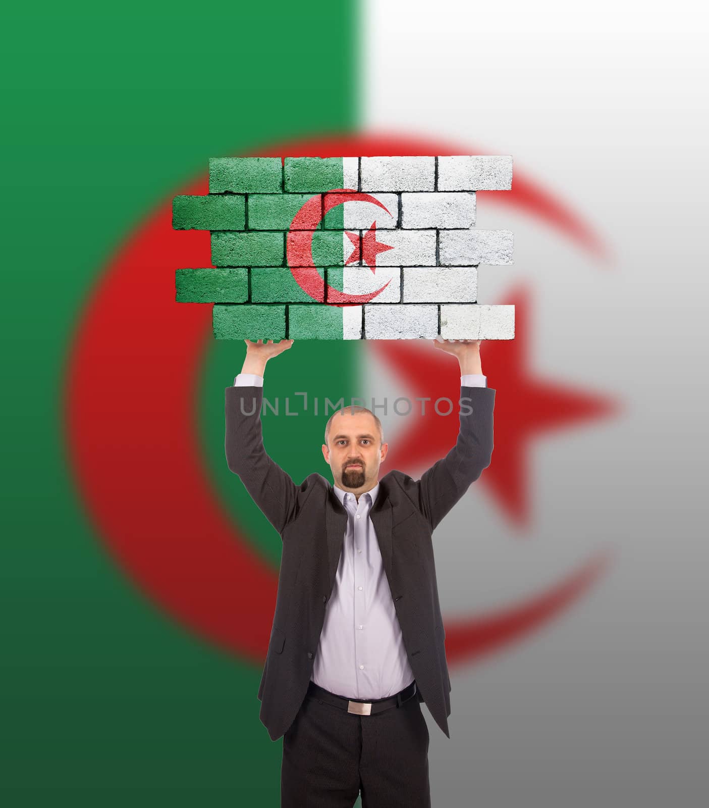 Businessman holding a large piece of a brick wall, flag of Algeria, isolated on national flag