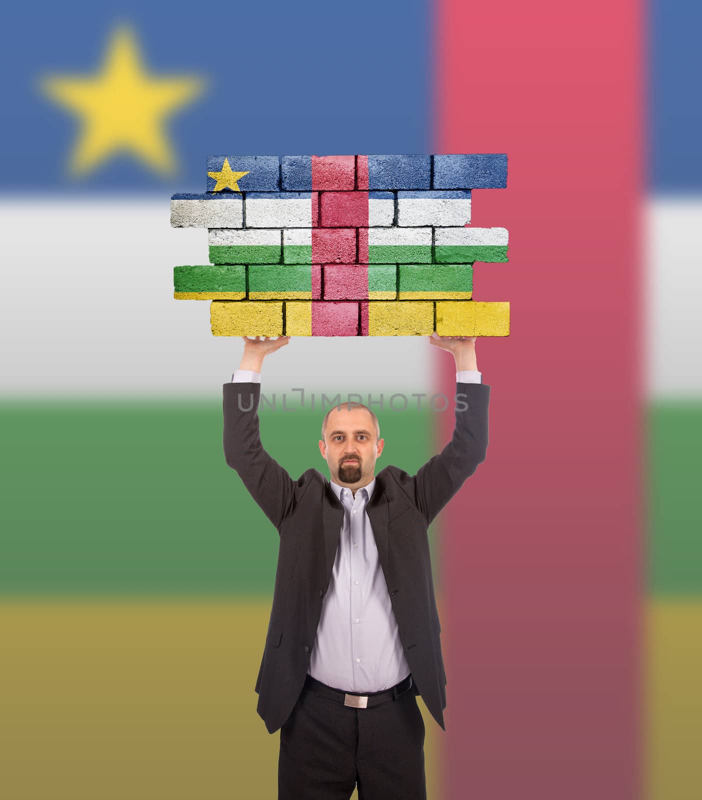 Businessman holding a large piece of a brick wall, flag of the Central African Republic, isolated on national flag