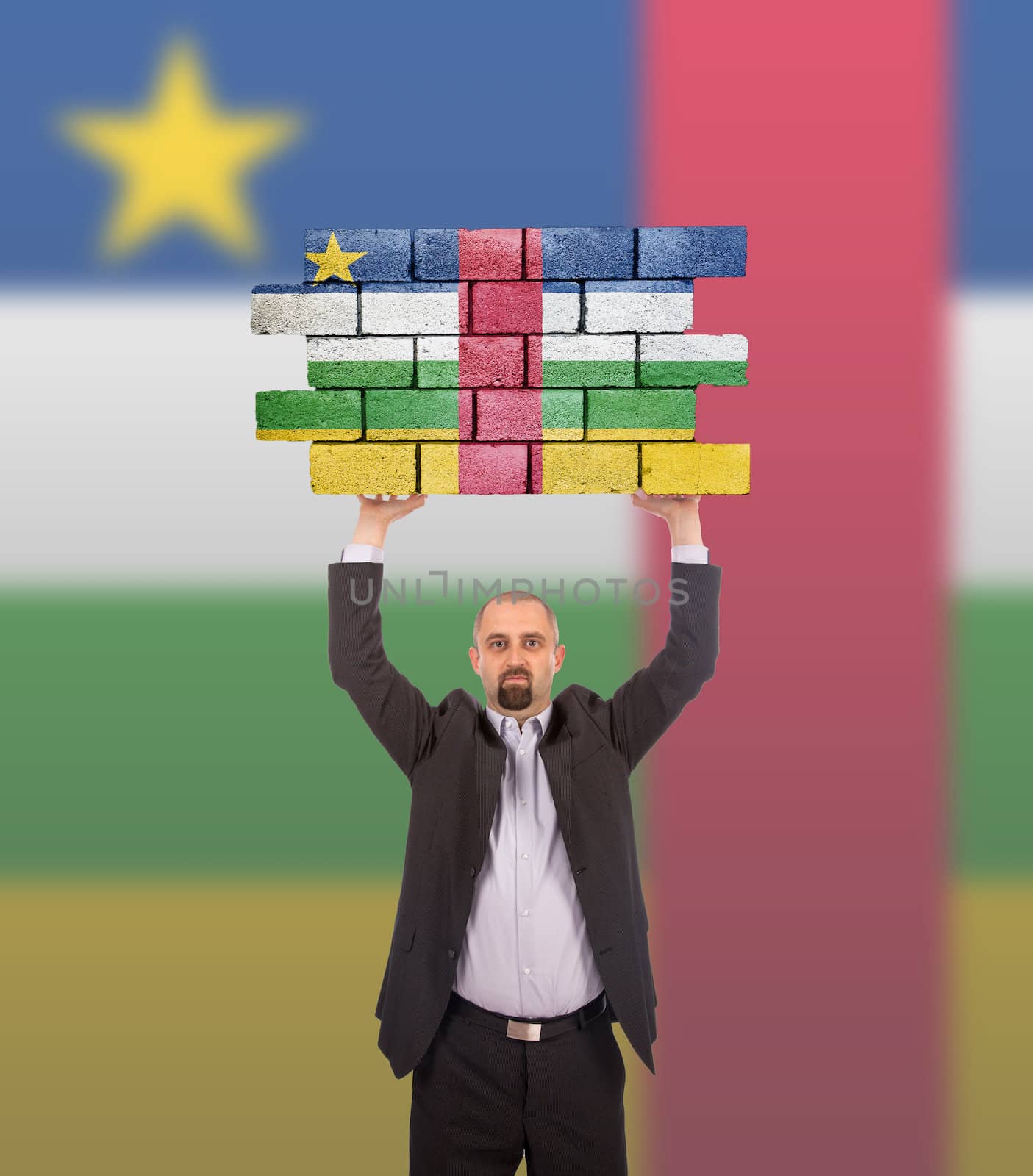 Businessman holding a large piece of a brick wall by michaklootwijk