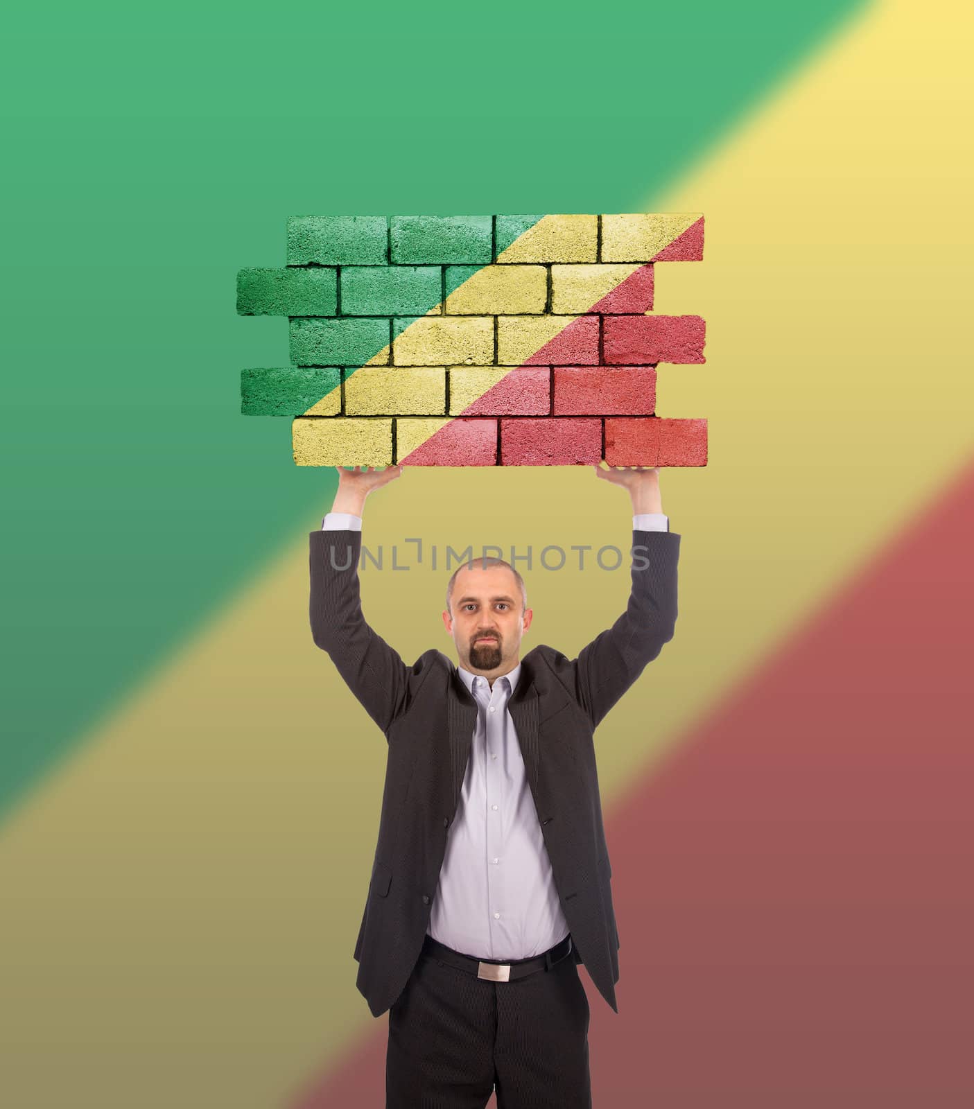 Businessman holding a large piece of a brick wall, flag of Congo, isolated on national flag